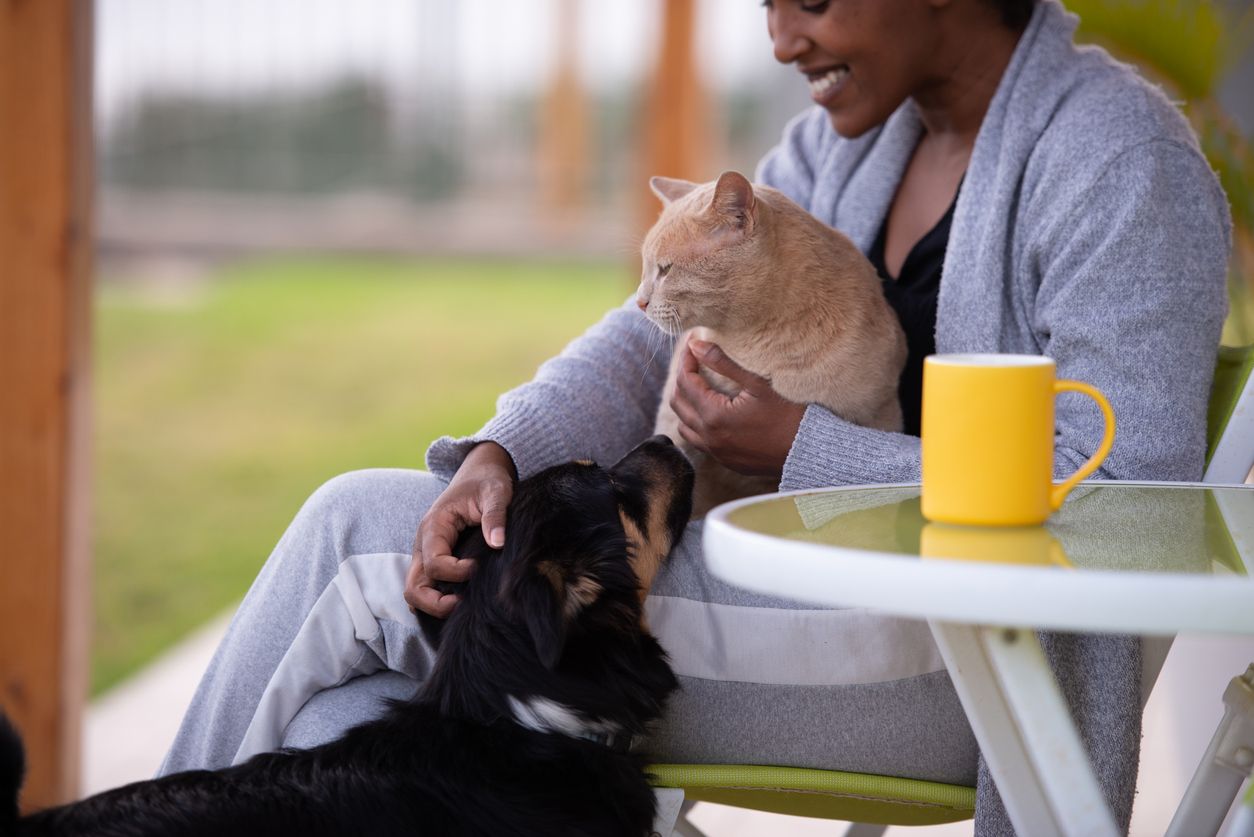A pet owner cuddles with her cat and dog