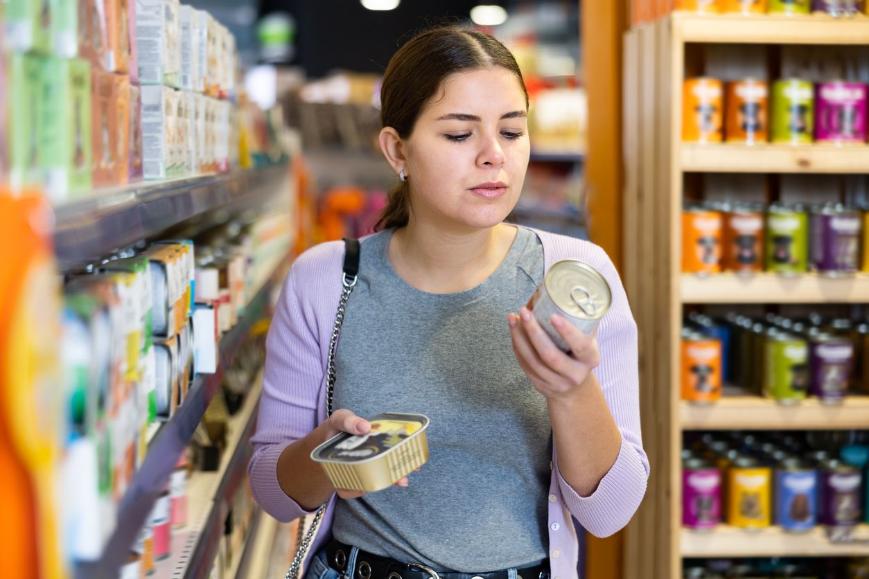 A pet parent considers the ingredients on a can of dog food