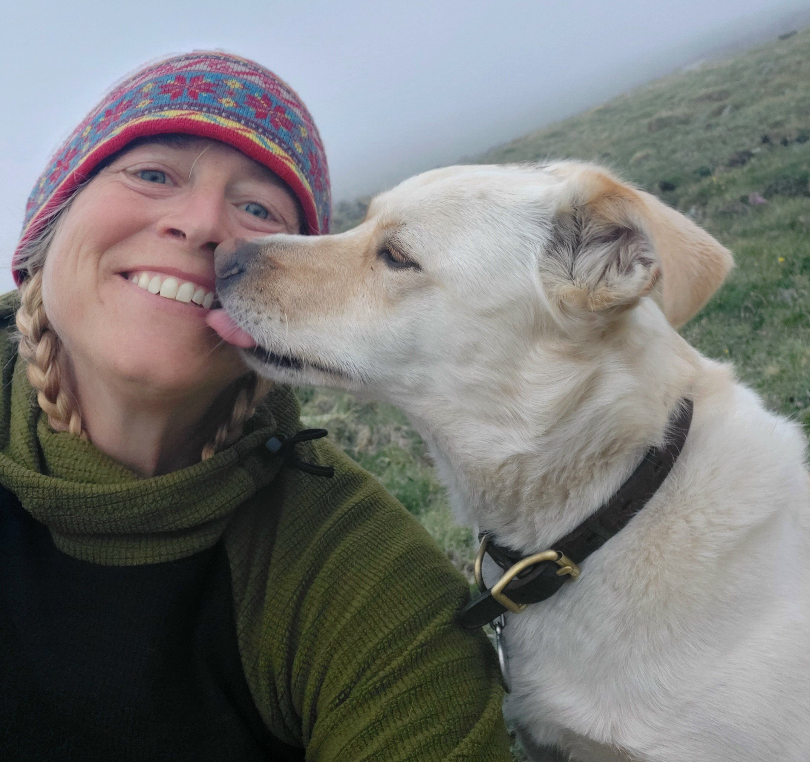 A picture of Jo Myers receiving kisses from Trio the dog